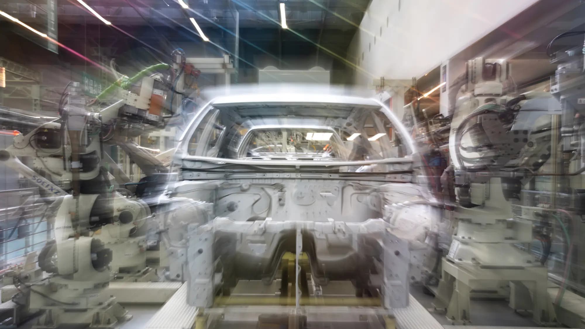 Una carrocería en una línea de montaje, entre brazos robóticos