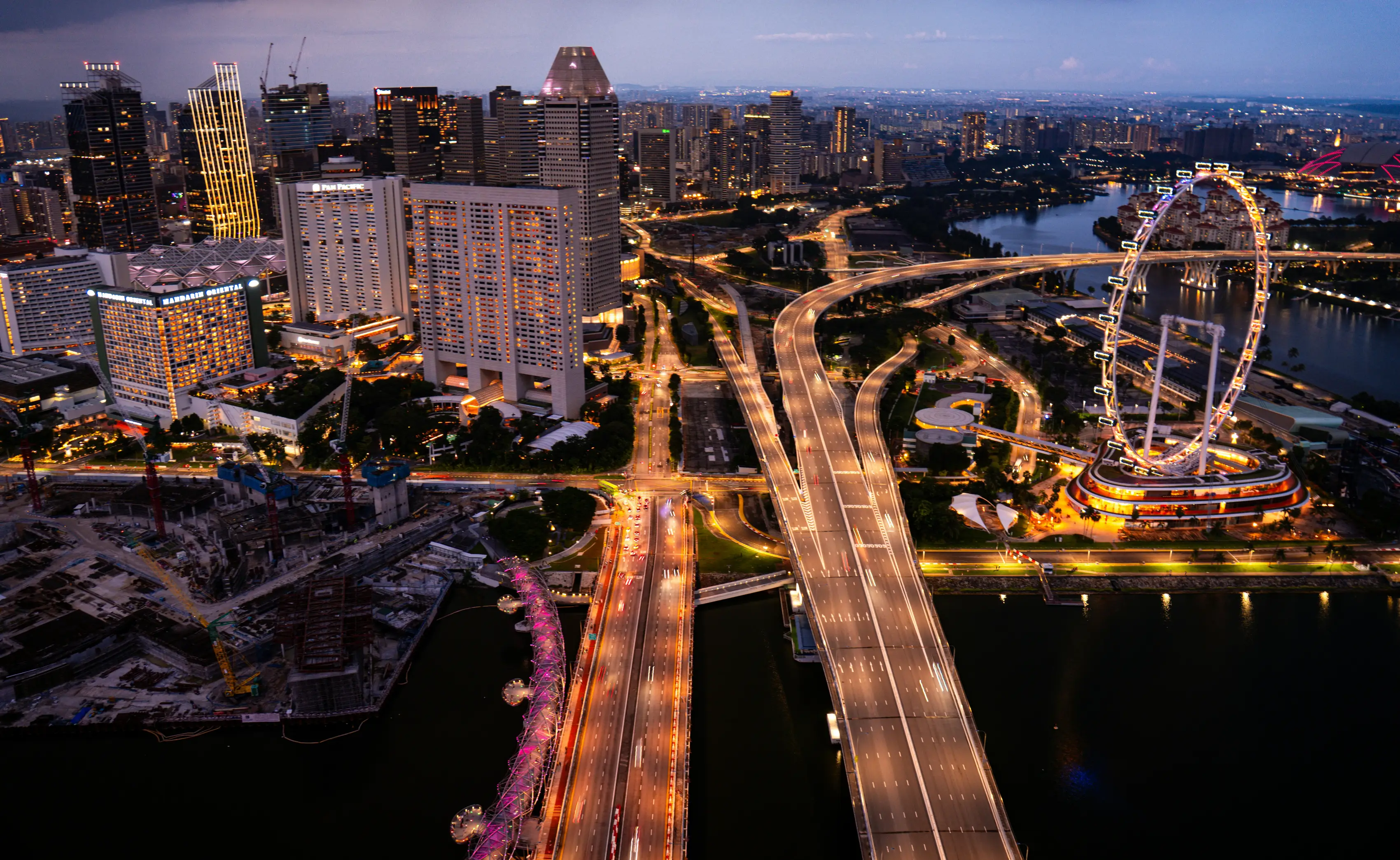 A city at dusk seen from the air, crossed by lit motorways.